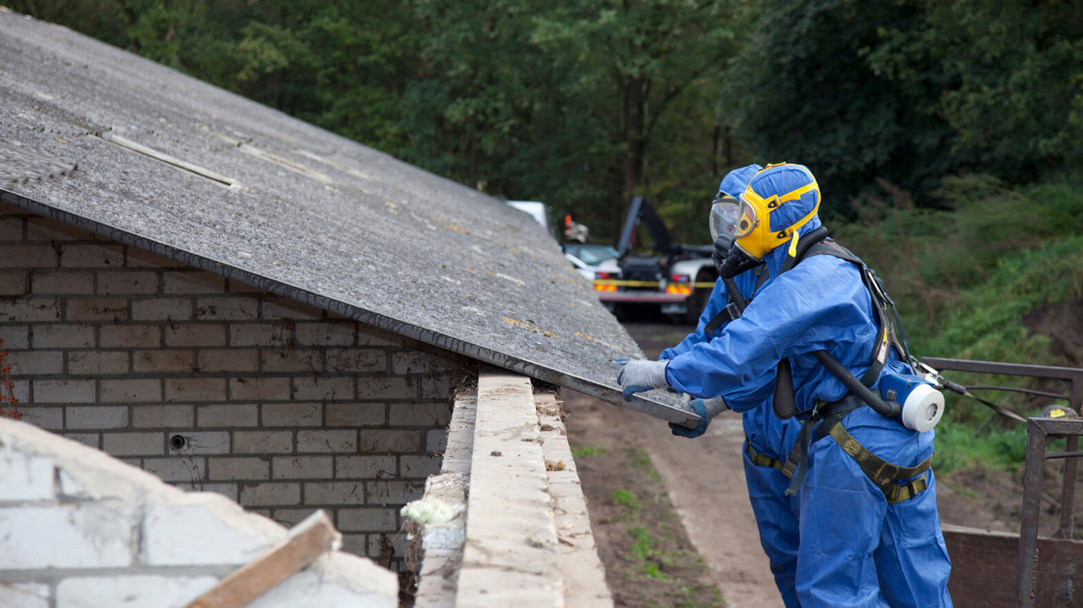 Two construction workers handle materials with asbestos