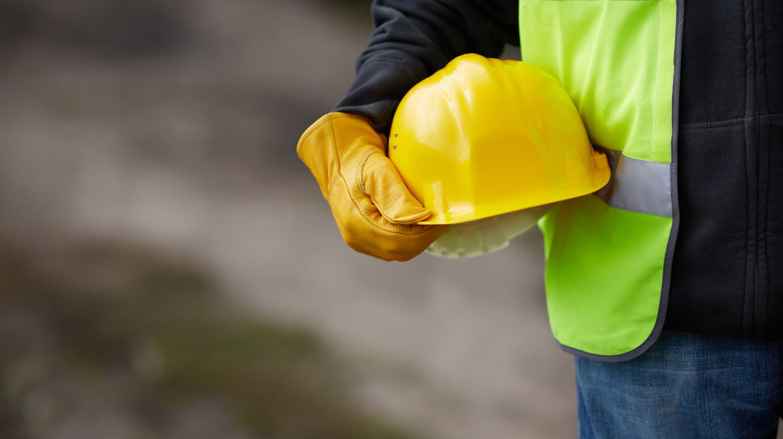 A contractor holding their hard hat against their waist