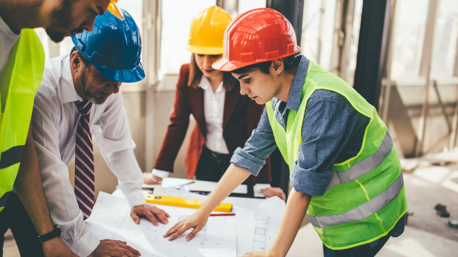 Construction workers studying blueprint designs for a building