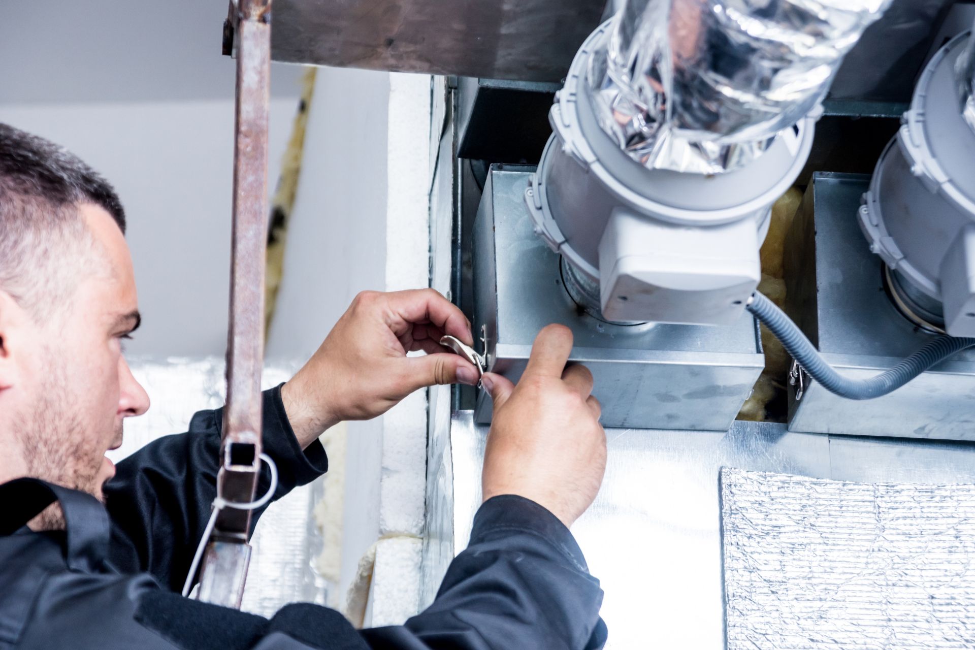 An HVAC technician working on a duct system 