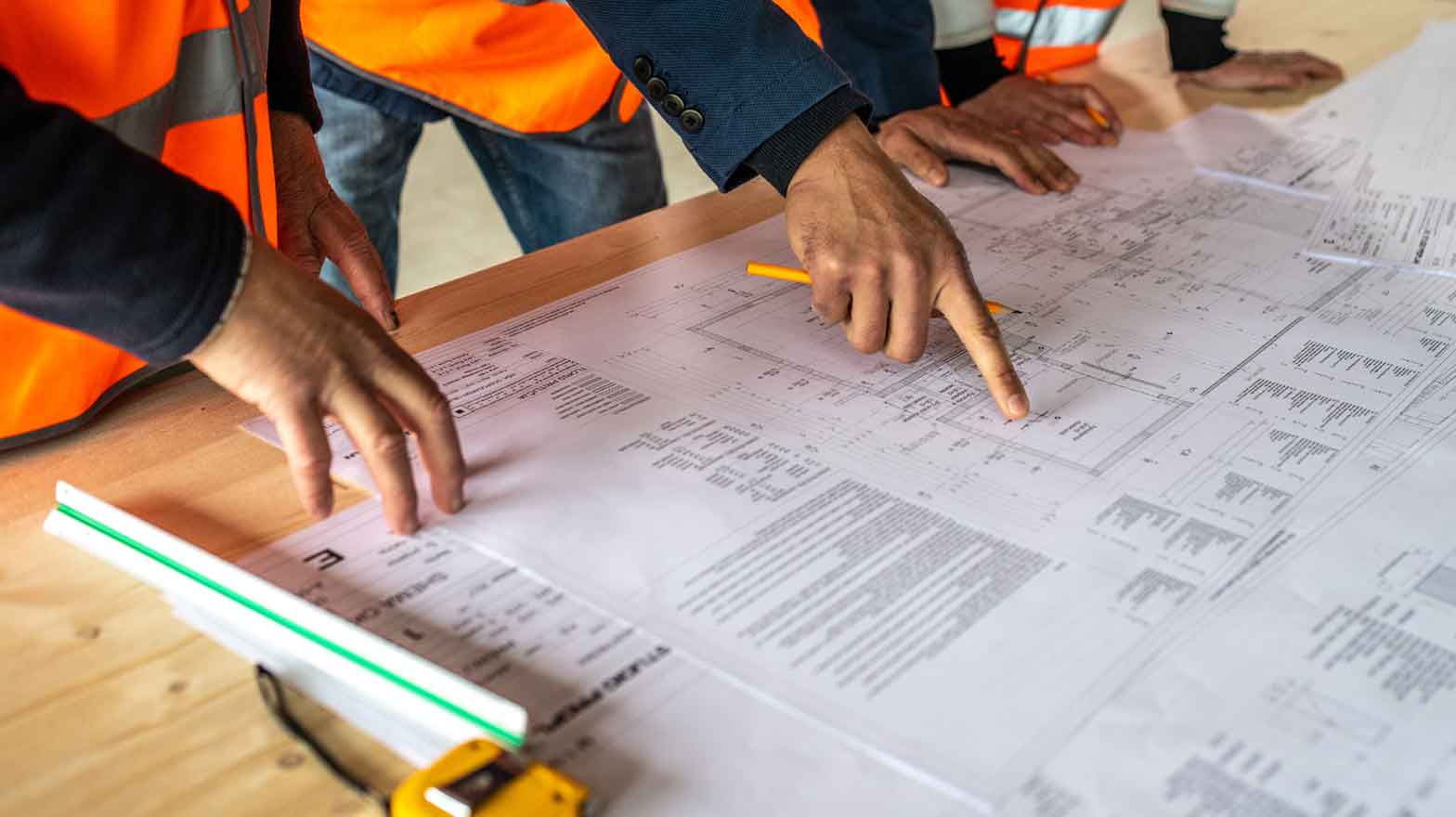 Three people discussing construction plans with a construction blueprint on a table