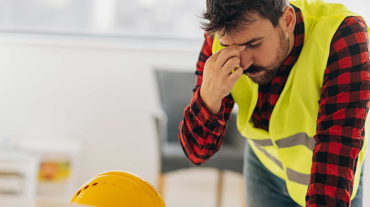 Contractor rubs his forehead while looking at a laptop