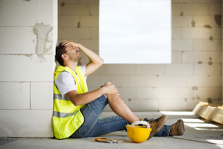 Injured person on the ground at a construction site holding their knee