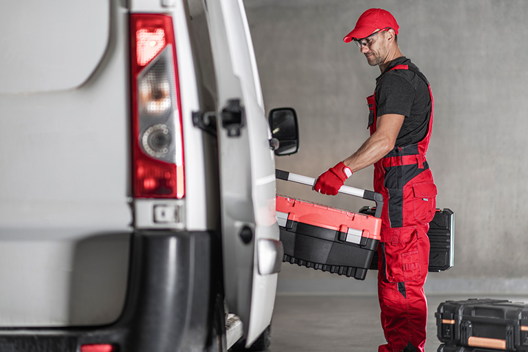 A mechanic putting toolboxes in a car