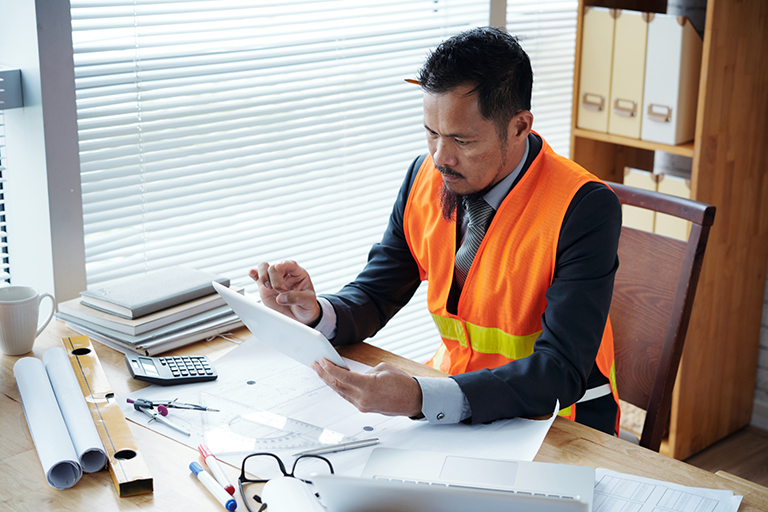 Construction manager going over documentation at a desk covered in papers