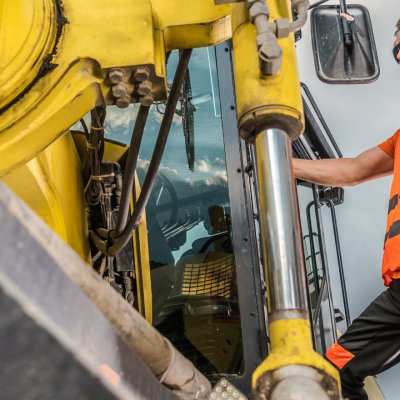 Heavy equipment operator getting inside leased heavy equipment