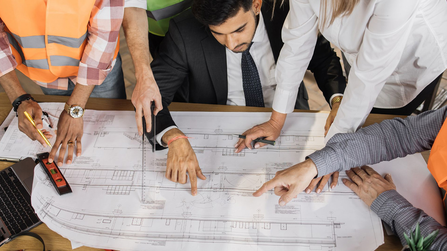 Group of Architects around a blue print pointing at a specific portion of the design