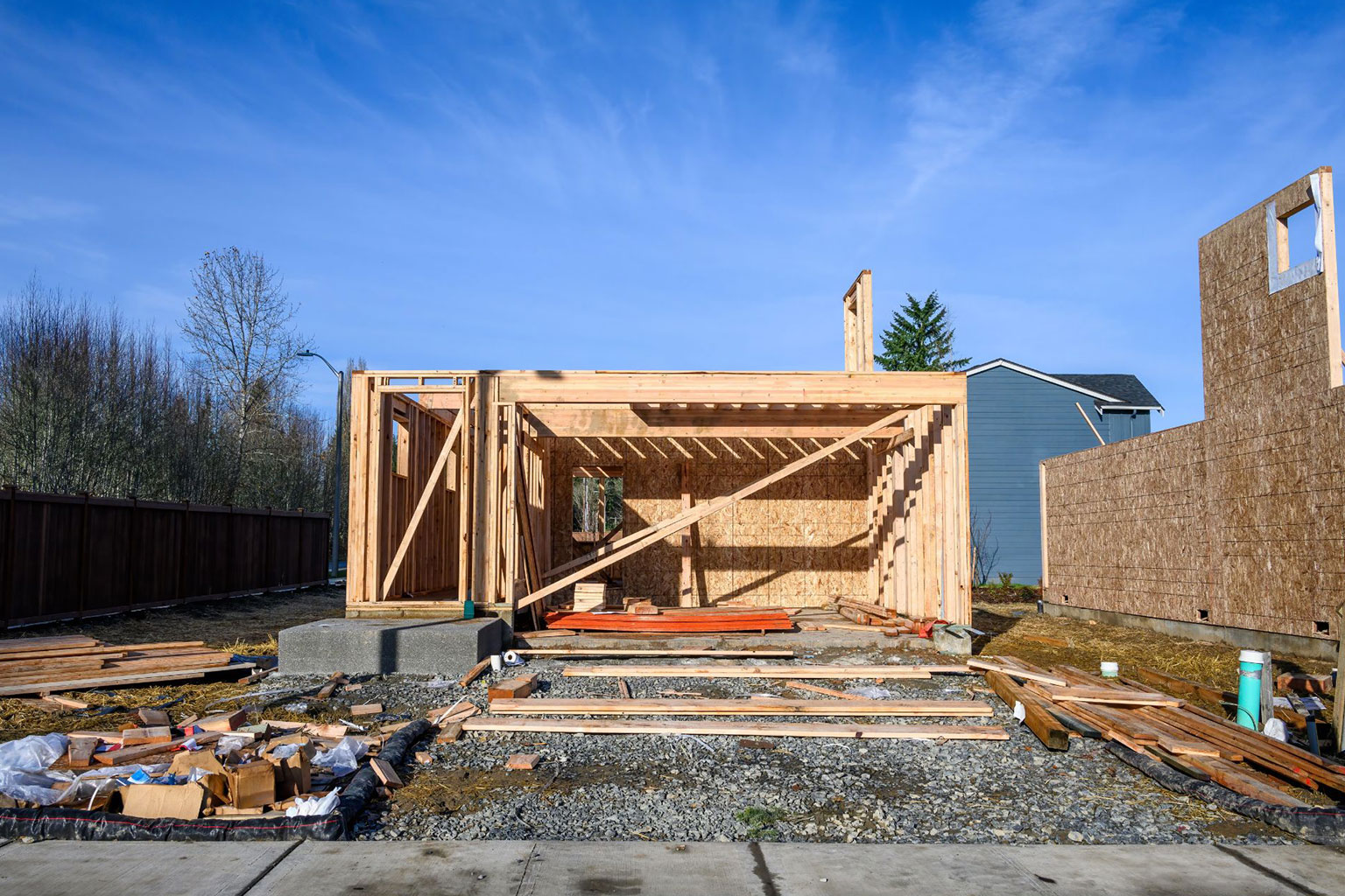 New housing development with wood frame, with waste materials in the front of the building.